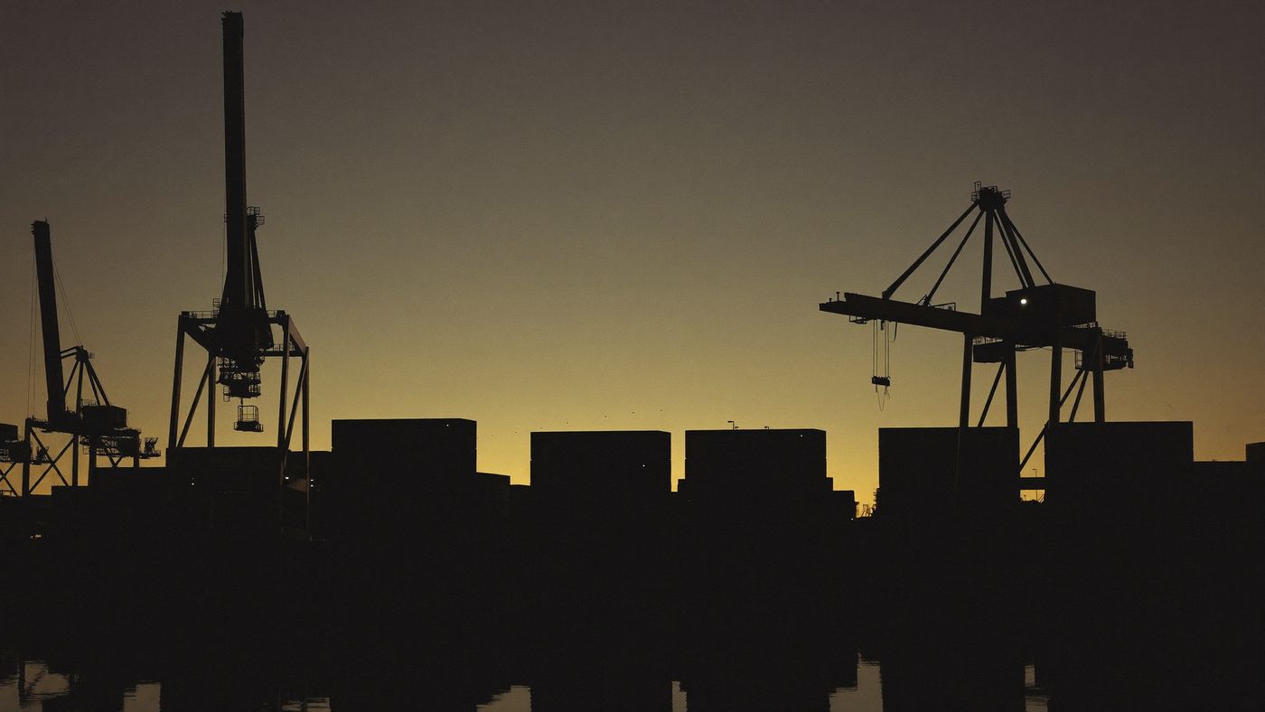 Container cranes silhouetted against a gold dusk sky